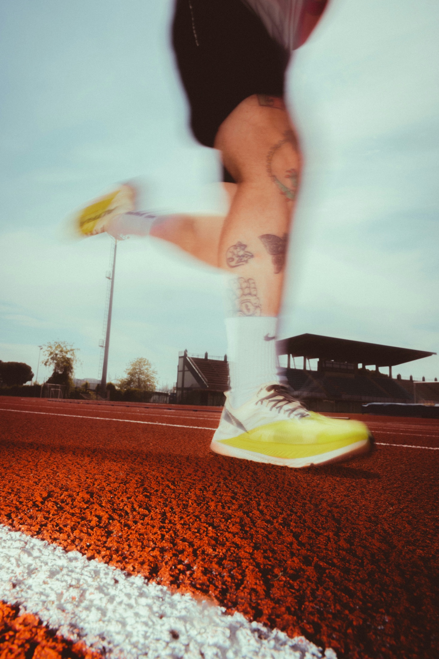 Sprinter accelerating on a red track in yellow spikes