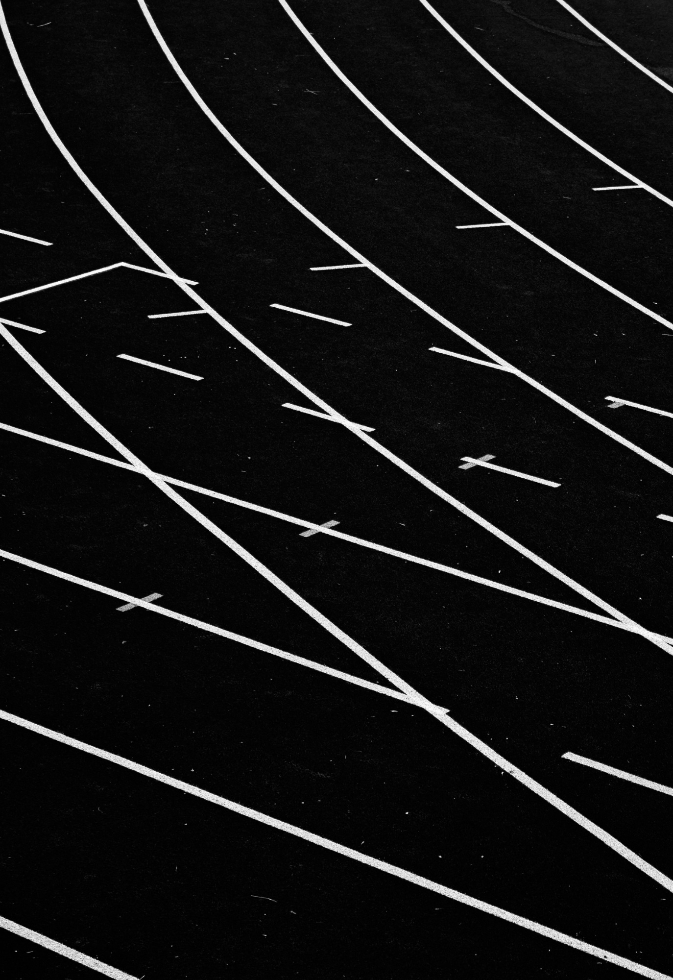 Track lane lines curving across black asphalt